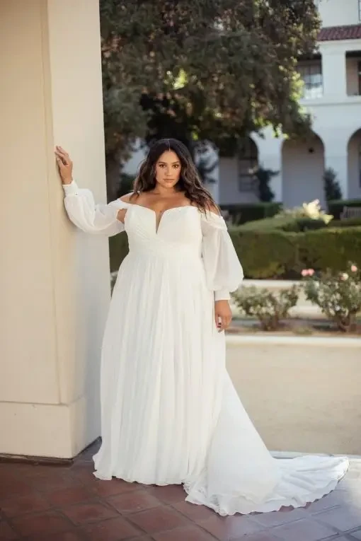 model is wearing an off the shoulder plus size wedding dress