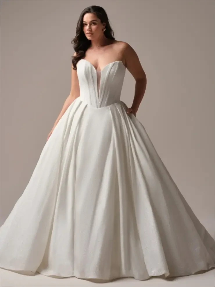 model is wearing a plus size strapless basque waist ball gown wedding dress