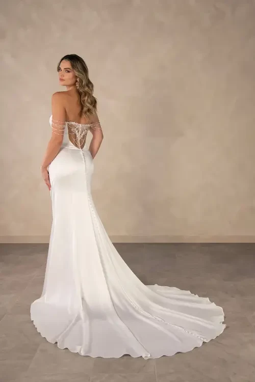 A woman in a white strapless gown with a train, standing against a neutral background.