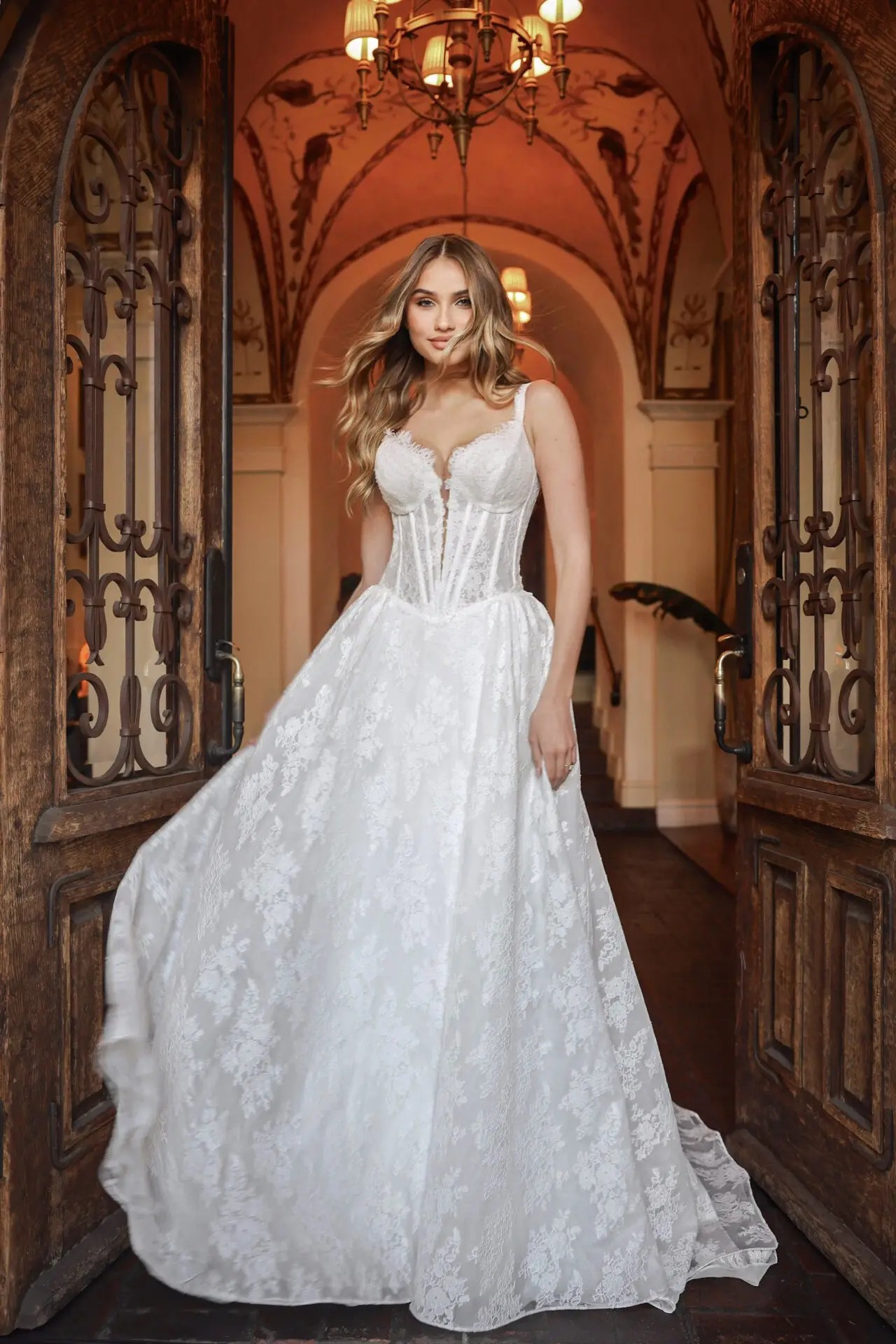 Model is wearing an a-line sleeveless wedding dress with a corset bodice and allover lace