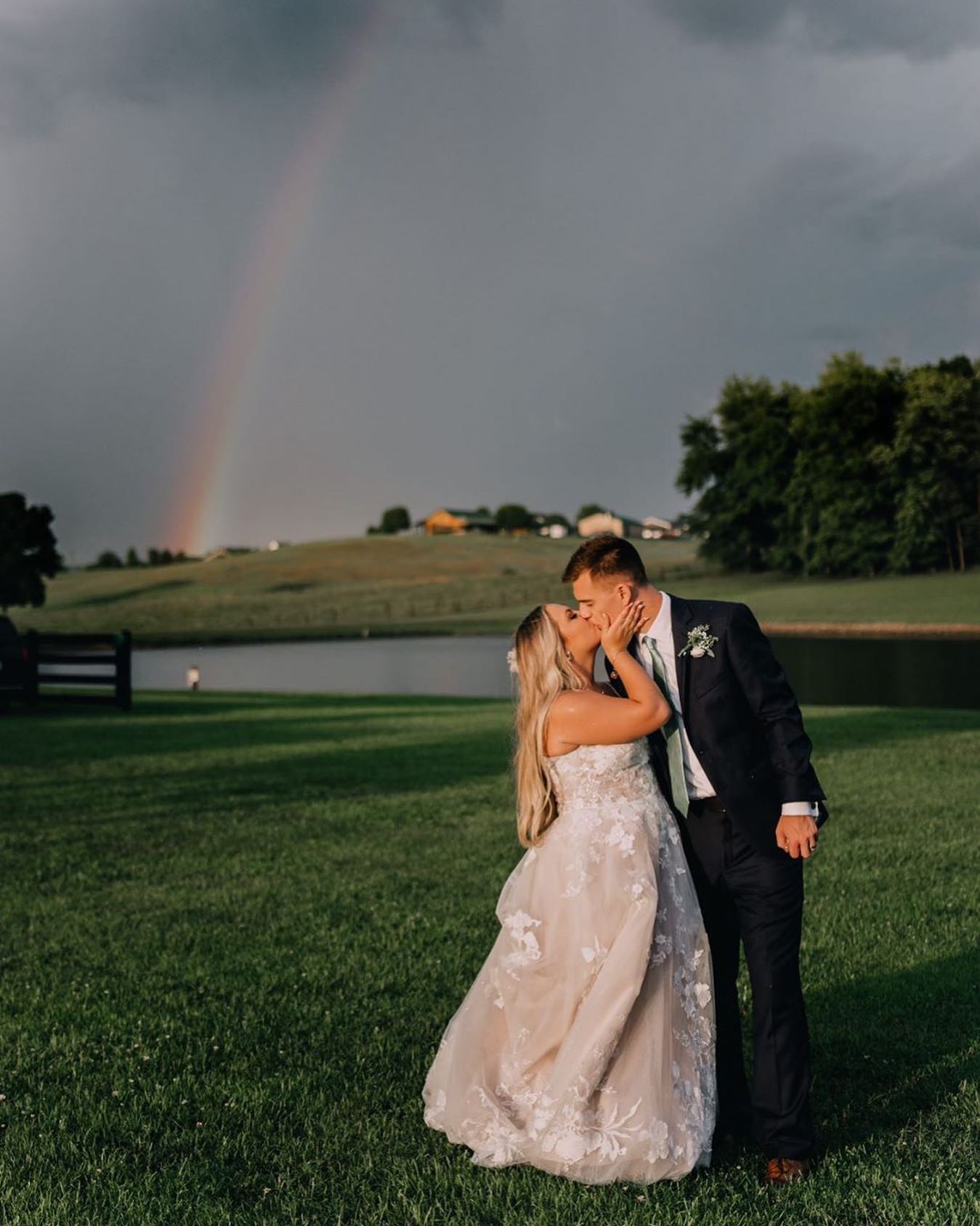 Photo of the real bride and groom kissing near the rainbow
