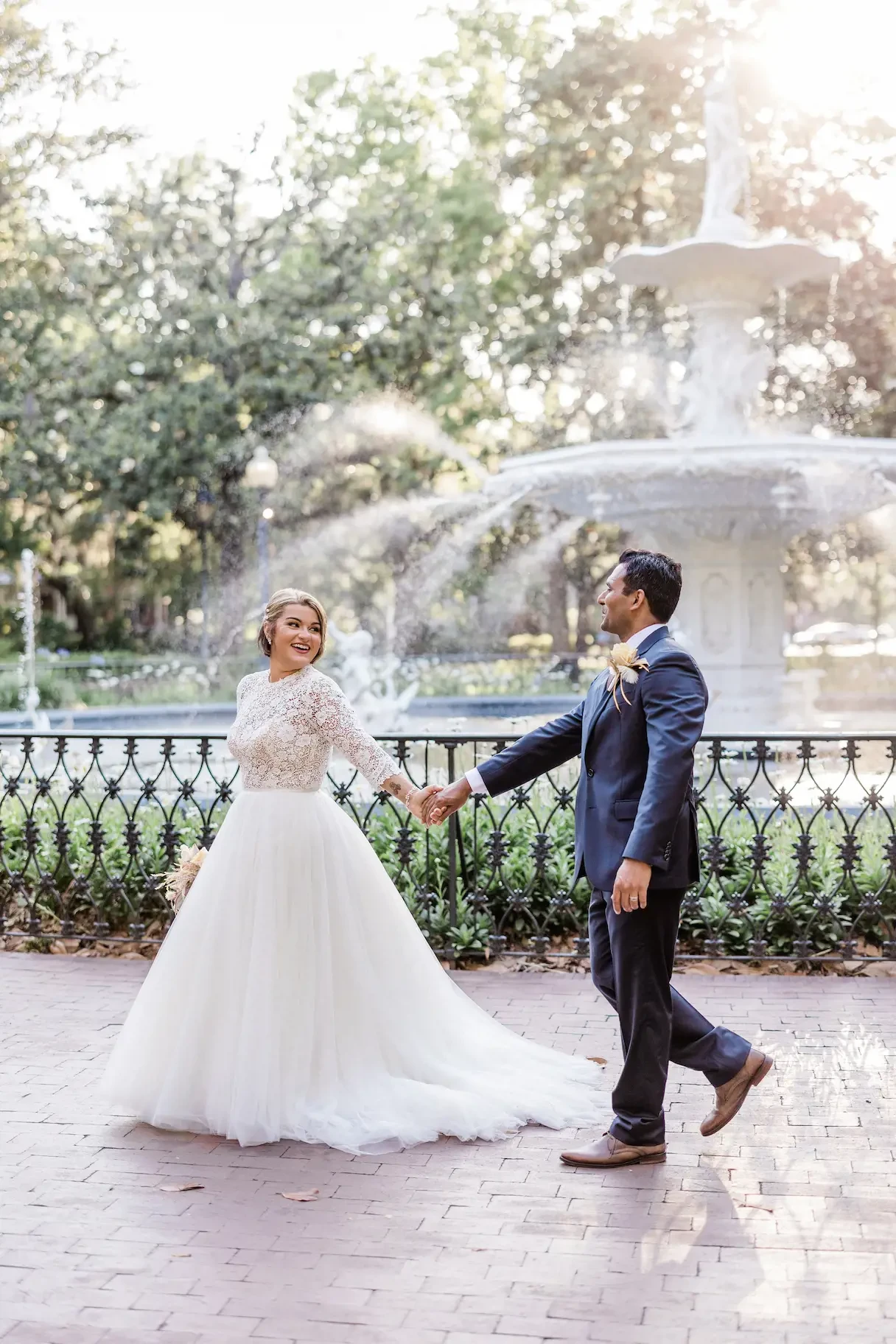 Photo of the real bride and groom walking near fountain